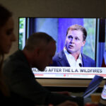 LA mayoral candidate Spencer Pratt is seen on a TV with the silhouettes of reporters in the foreground.