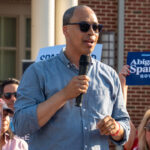 Jay Jones in blue shirt and sunglasses speaks at a 2025 campaign event.