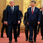 President Donald Trump and Chinese leader Xi Jinping walk together on a red carpet inside China's Great Hall.