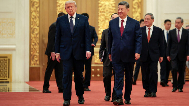 President Donald Trump and Chinese leader Xi Jinping walk together on a red carpet inside China's Great Hall.