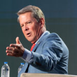 Georgia Gov. Brian Kemp gestures while speaking at a podium.