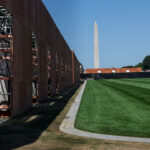 A temporary wooden fence surrounds a section of the National Mall, with the Washington Monument in the background.