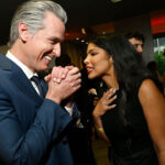 Gavin Newsom clasps his hands with glee while talking to Olivia Igbokewe Curry.