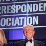 A beaming Donald Trump along with Melania Trump stand at the White House Correspondents' Association dinner.