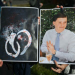 People hold up a photo of British murder victim Henry Nowak next to a photo of his bloody handcuffs.