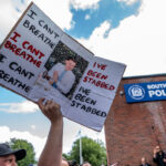 Arm holds up sign featuring image of Henry Nowak ringed with phrases "I can't breathe" and "I've been stabbed."