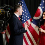 Daily Signal's Mehek Cooke interviews DOJ's Colin McDonald in front of American and Ohio flags.