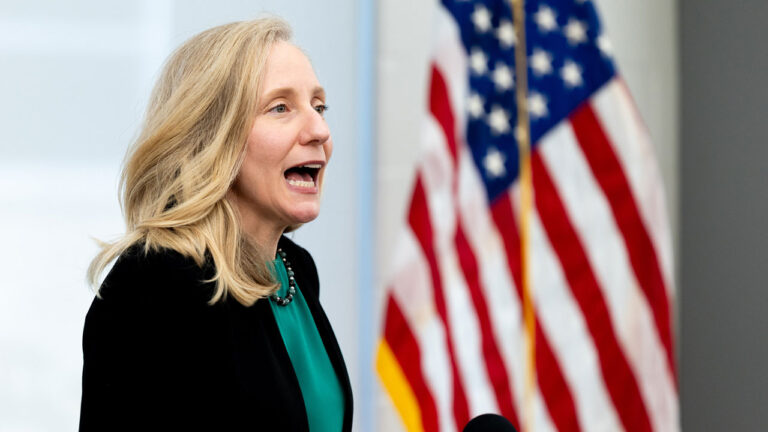 Abigail Spanberger with her mouth open, American flag in the background.