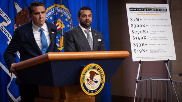 Todd Blanche at a podium with Kash Patel at his side as they announce charges against SPLC.