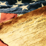 The Declaration of Independence laying upon an old American flag.