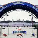The Claw, part of the area for UFC Freedom 250 arches over the White house and a red, white and blue sign promoting the event.