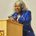 Virginia President Pro Tempore L. Louise Lucas speaks at a tan podium.