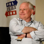 Bill Kristol sits with his arms folded while in a white shirt.