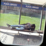 A bus window frames a person napping on the Plaza Library bench. The Kansas City Area Transportation Authority (KCATA) bus is free for all riders. (Photo by Pat Greenhouse/The Boston Globe via Getty Images)