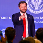 JD Vance in blue jacket and red tie points into the audience with a smile at the Richard Nixon Presidential Library.