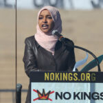 Ilhan Omar in brown leather jacket speaks at a podium reading "No Kings."