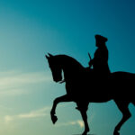 Silhouette of George Washington on his horse against a blue background.