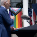 US President Joe Biden speaks during a Pride celebration on the South Lawn of the White House in Washington, DC, on June 10, 2023. Trans flag flying next to American flags.