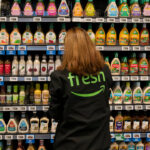 An employee arranges a salad dressing display at an Amazon Fresh grocery store on December 12, 2024 in Federal Way, Washington. Amazon recently held grand re-opening events for three redesigned Amazon Fresh stores in the Puget Sound region. (Photo by David Ryder/Getty Images)