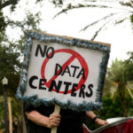 A person holds signs during a nationwide protest against AI data center expansion outside Peace Hall in New Port Richey, Florida on July 18, 2026. (Photo by Thomas Simonetti / AFP via Getty Images)