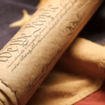 The U.S. Constitution, rolled up, rests on an American flag.