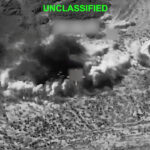 Black-and-white aerial view shows a large explosion with smoke billowing from the ground in a rugged, desert-like landscape. The word UNCLASSIFIED is displayed at the top in green text.