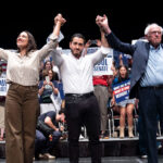 Alexandria Ocasio-Cortez (D-NY), Michigan Democratic candidate for Senate Abdul El-Sayed and U.S. Sen. Bernie Sanders (I-VT) raise their arms during a rally.