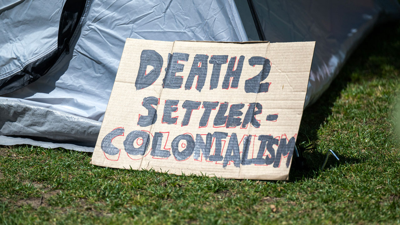 A Gaza solidarity encampment sign reads 'Death to Settler Colonialism.'