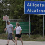 OCHOPEE, FLORIDA - APRIL 22: People walk near the front entrance to the immigration detention center in the Florida Everglades known as “Alligator Alcatraz" on April 22, 2026, in Ochopee, Florida. A federal appeals court overturned an injunction by a district court judge requiring officials to dismantle “Alligator Alcatraz” in response to a lawsuit filed by environmental groups. (Photo by Joe Raedle/Getty Images)