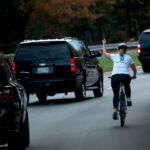 Juli Briskman shows her middle finger as a motorcade with US President Donald Trump on October 28, 2017.
