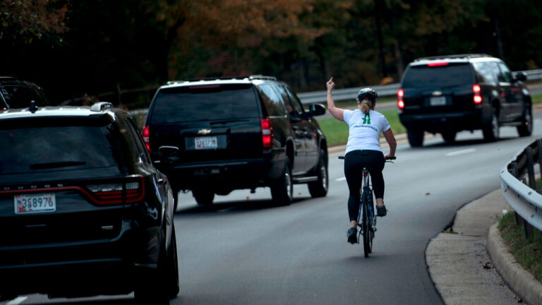 Juli Briskman shows her middle finger as a motorcade with US President Donald Trump on October 28, 2017.