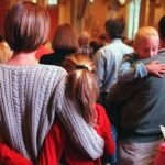 A family holds each other while attending a church service.