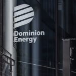 The Dominion Energy logo and name are displayed on the glass entrance of a modern building, with reflections and metal railings visible nearby.