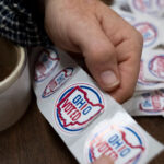 A hand is shown tearing through "Ohio Voted" stickers.