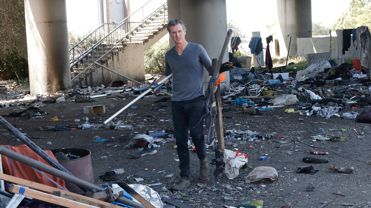Governor Gavin Newsom picks up trash in an underpass.