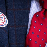 A man's navy suit with red and blue tie features an "OHIO VOTED" sticker.