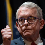 Ohio Gov. Mike DeWine stands with his thumbs up.