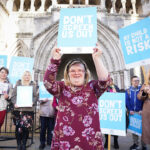 Girl standing with a sign saying, "Don't Screen Us Out."