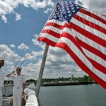 Lt. Paul Brawley, Seaman Deville Warner, and ENS Christopher Bongard salute the flag
