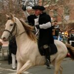 A Paul Revere reenactor rides on a horse