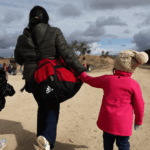 An immigrant and her two daughters walk along the U.S. Mexico Border.