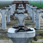 The unfinished high speed rail concrete columns stand in a vast green field.