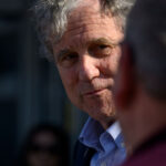 Sherrod Brown, an Ohio Democrat, looks on at another person.