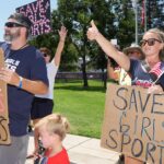 Protesters with signs saying "save girls sports"