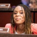 Shontel Brown smiles as she looks ahead while sitting for a committee hearing.