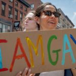 Woman holding a sign that says "I am gay"
