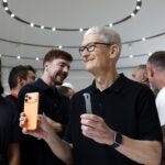 Apple CEO Tim Cook holding iPhones while surrounded by people