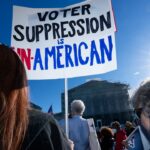 Protestors with a sign that says "Voter suppression is un-American"