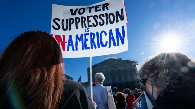 Protestors with a sign that says "Voter suppression is un-American"