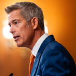 Side view of Transportation Secretary Sean Duffy as he speaks from the podium.